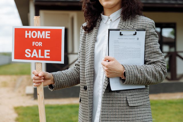 a real estate broker holding a home for sale sign